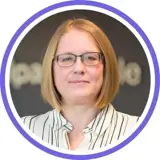 A headshot of a smiling ginger lady wearing a white and black stripey shirt and glasses with a purple ring around the image.