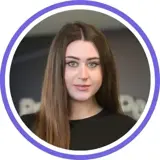 A headshot of a smiling brunette woman wearing all black with a purple ring around the image.